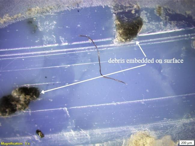 Optical micrograph of plain rPET with burnt patches, smearing and embedded debris.