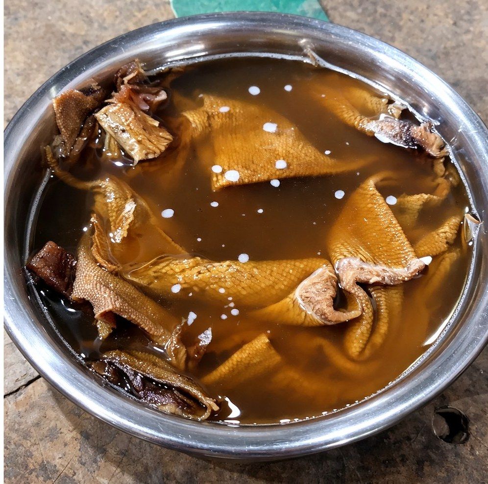 Natural-fibre fabric soaking in brown alkali solution in a steel bowl