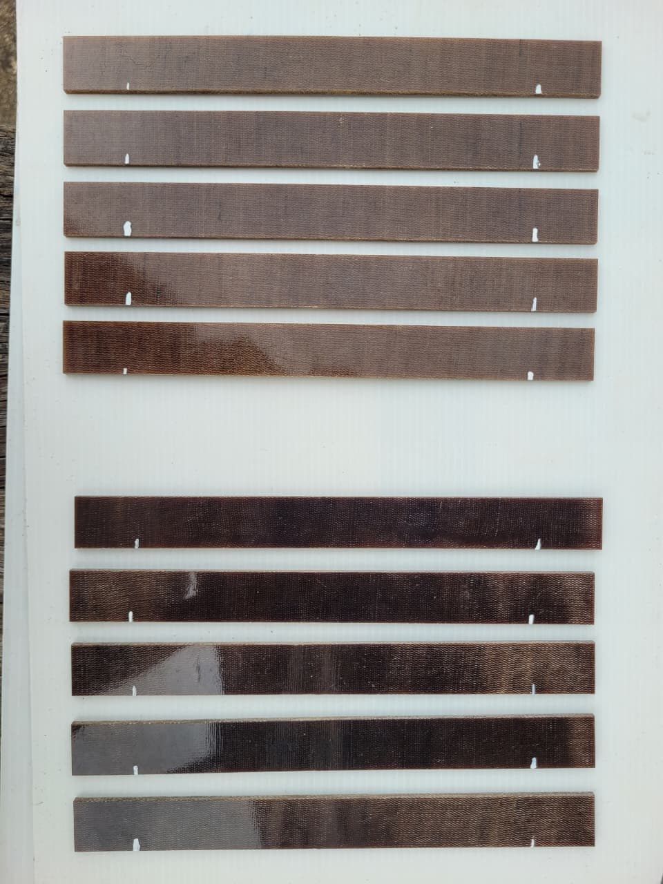 Ten cut tensile specimens in two rows on a white board